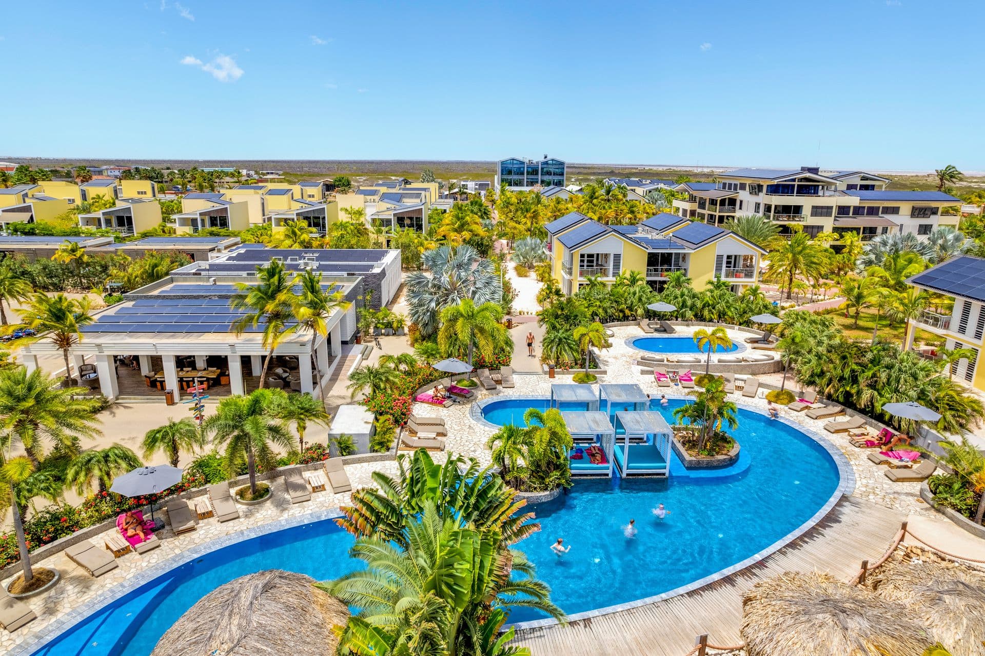 Groot zwembad tussen palmen en de gebouwen van het resort
