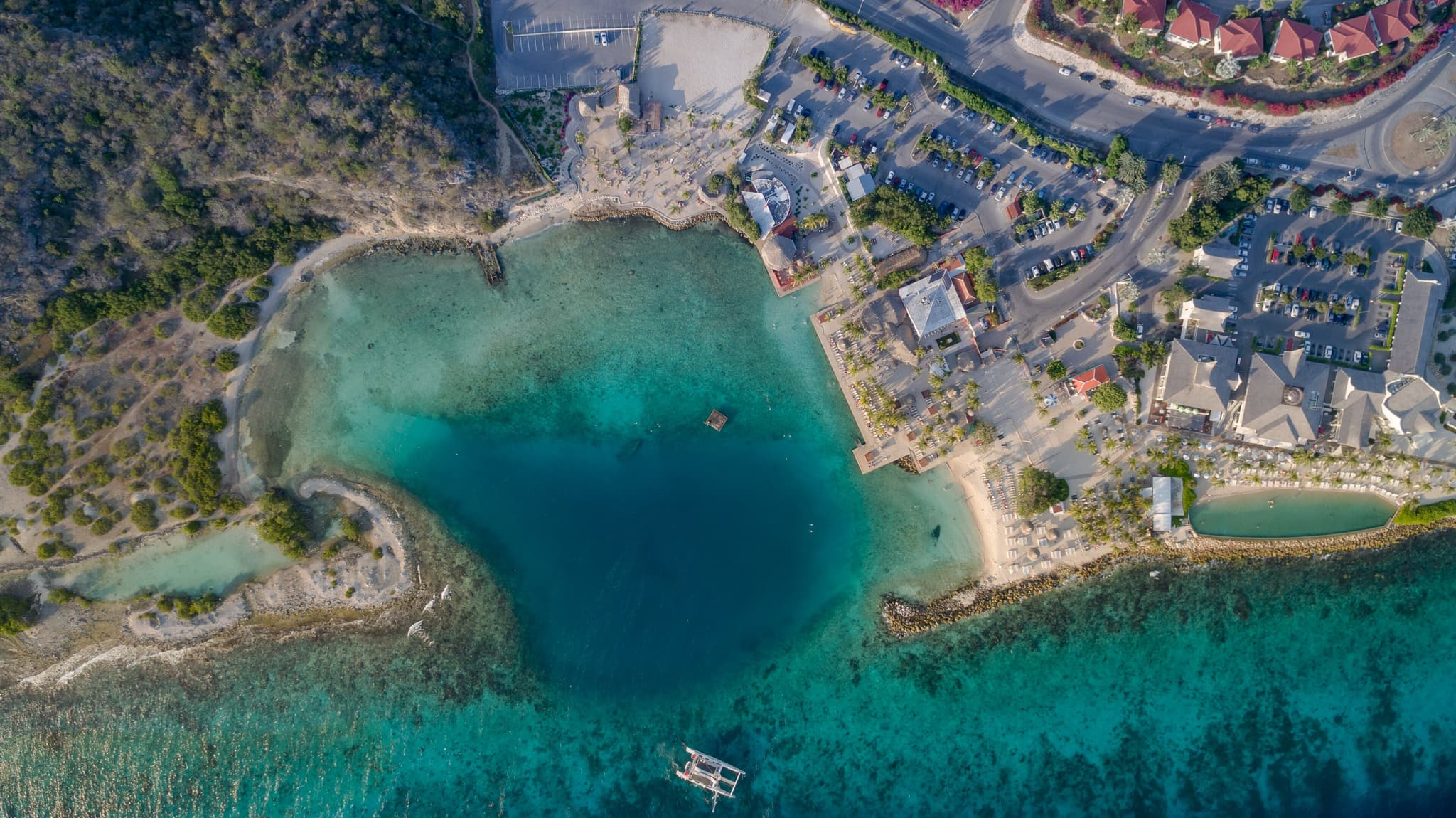 Baai en kustlijn bij Jan Thiel vanuit de lucht, met resorts aan het water