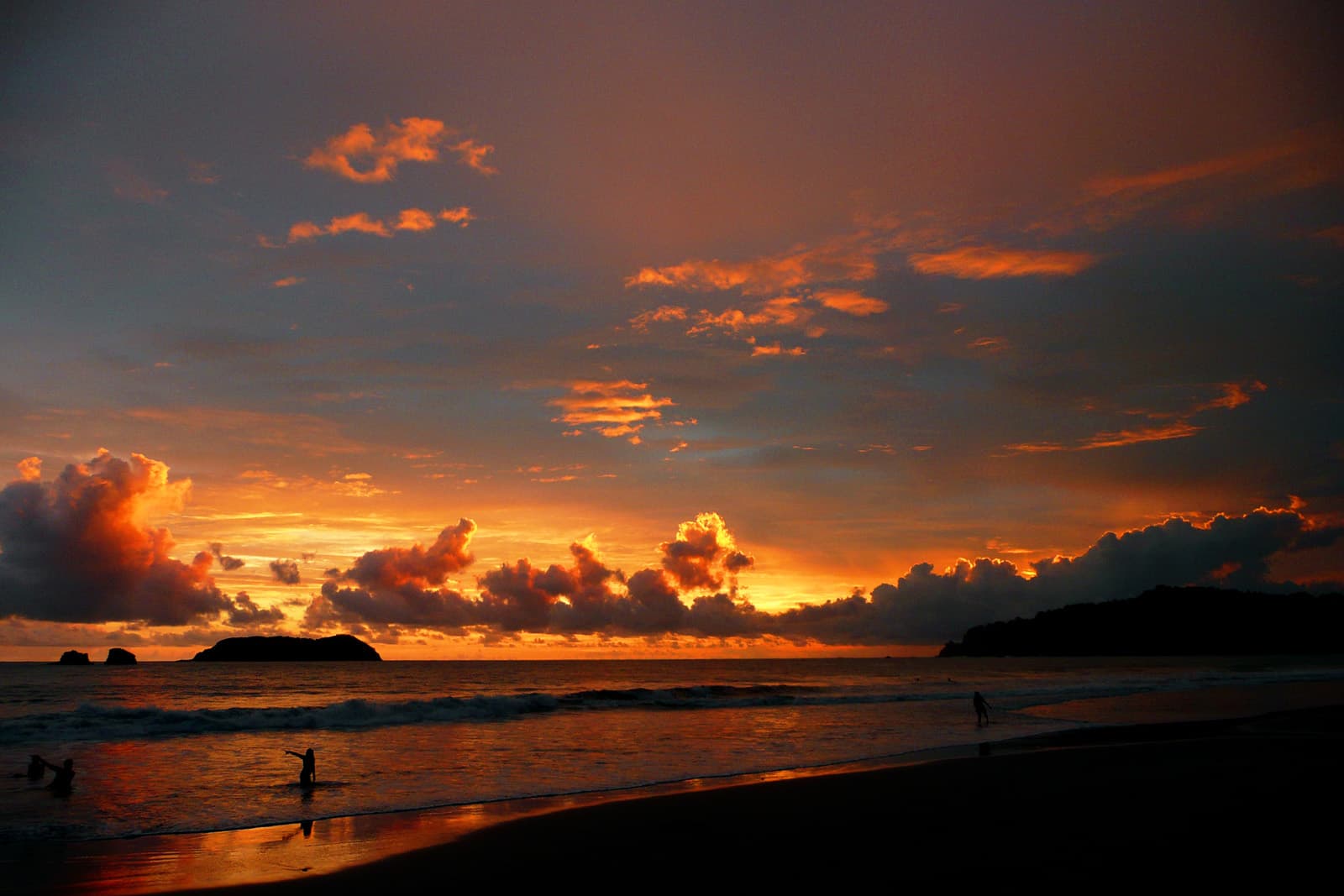 Zonsondergang boven het strand bij Manuel Antonio, met silhouetten aan de waterlijn